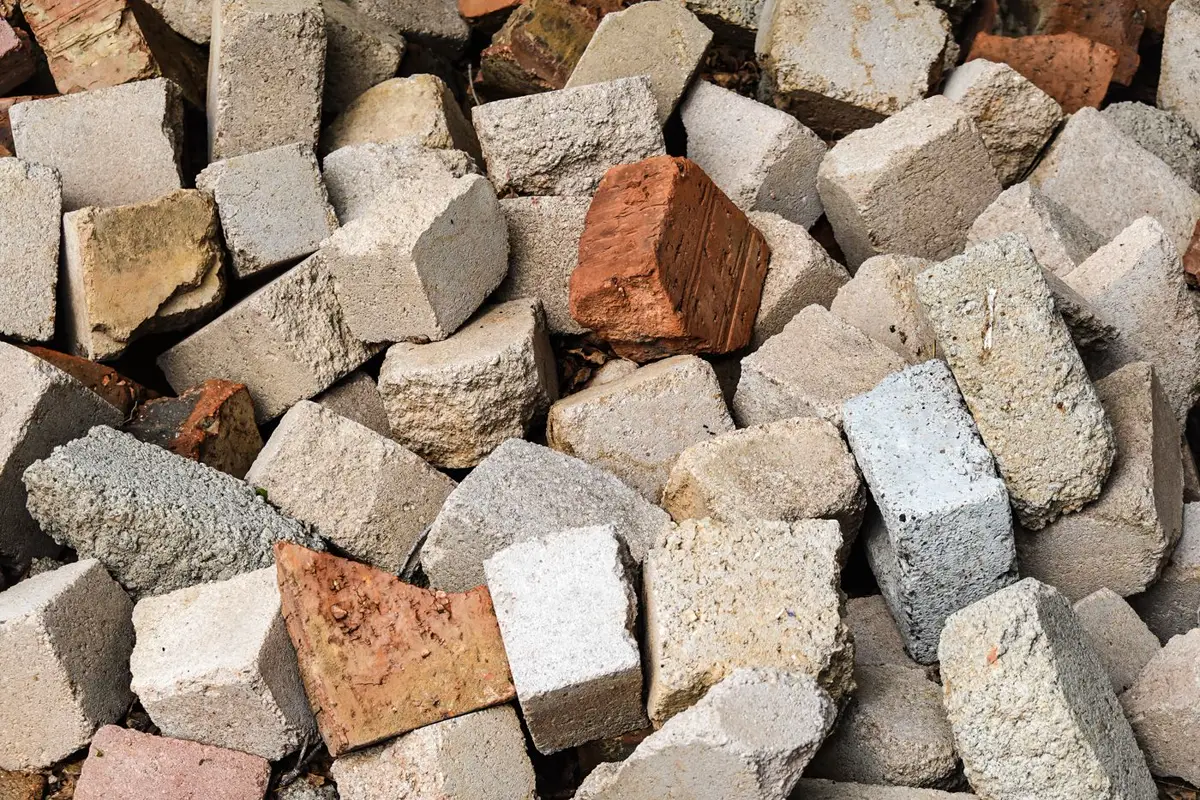 A pile of broken grey concrete blocks mixed with red clay bricks.